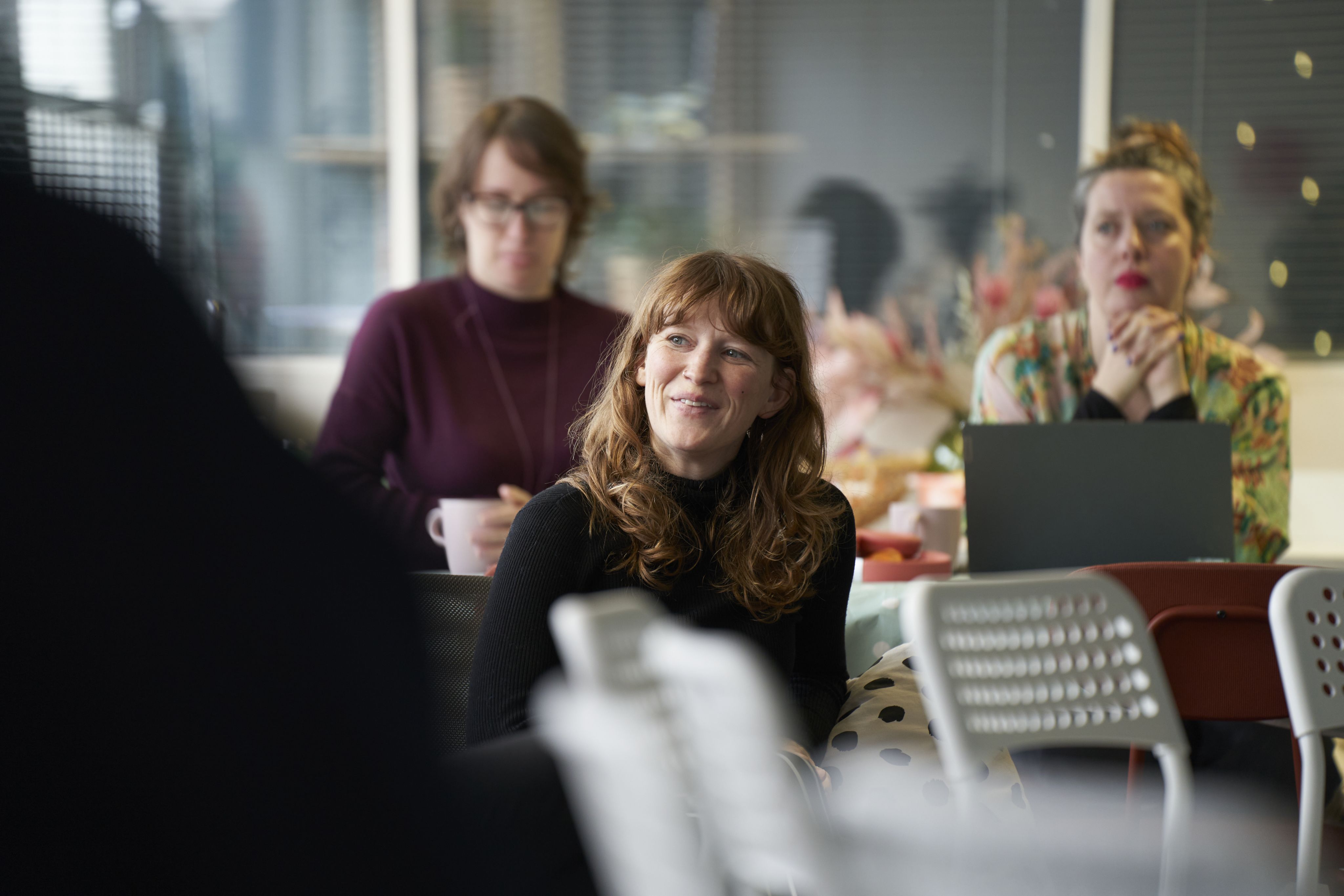 3 healthcare professionals listening during a Sands Training session. The woman at the front is smiling.