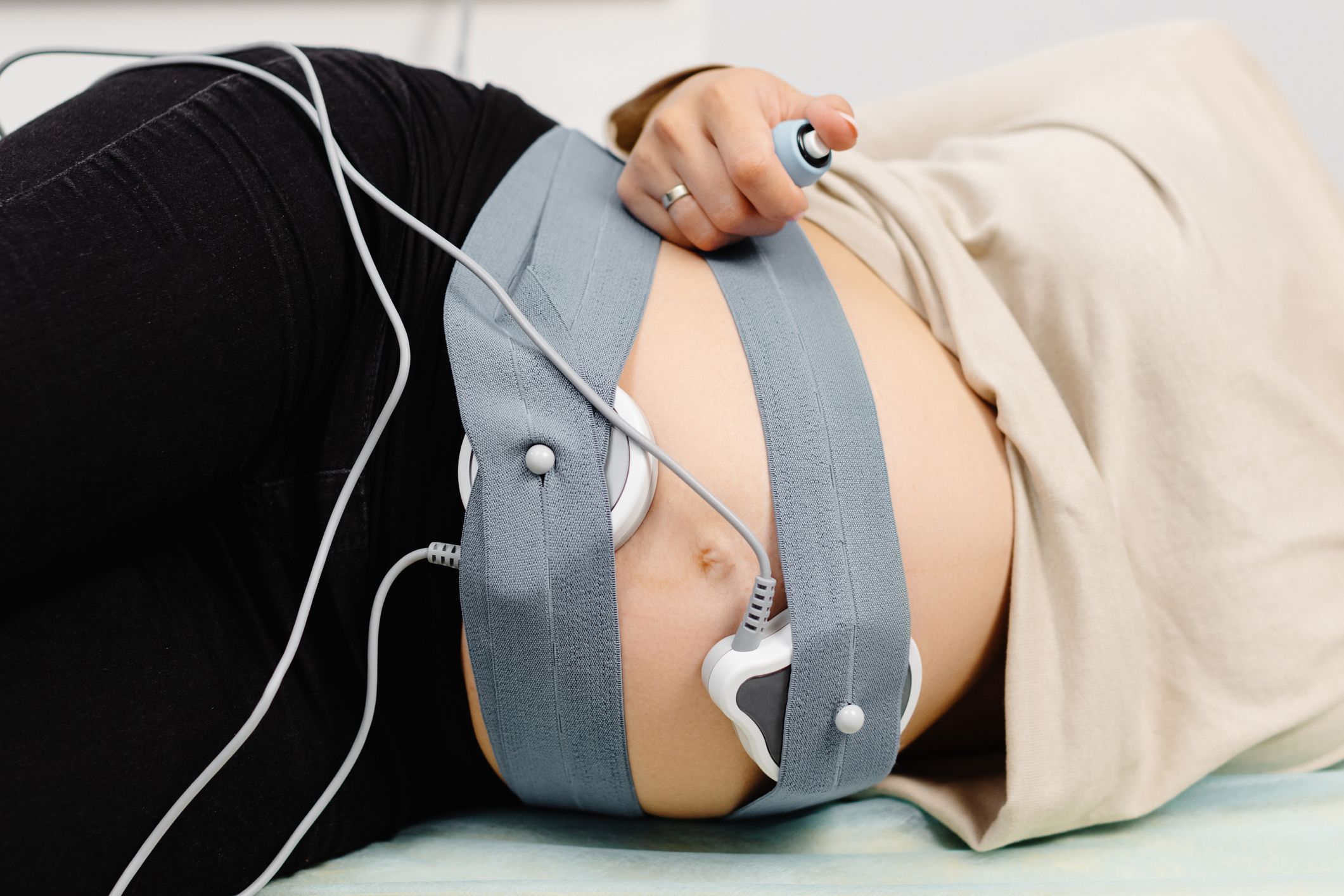 A pregnant woman lies on a hospital bed undergoing a test to monitor her baby’s heartbeat. 