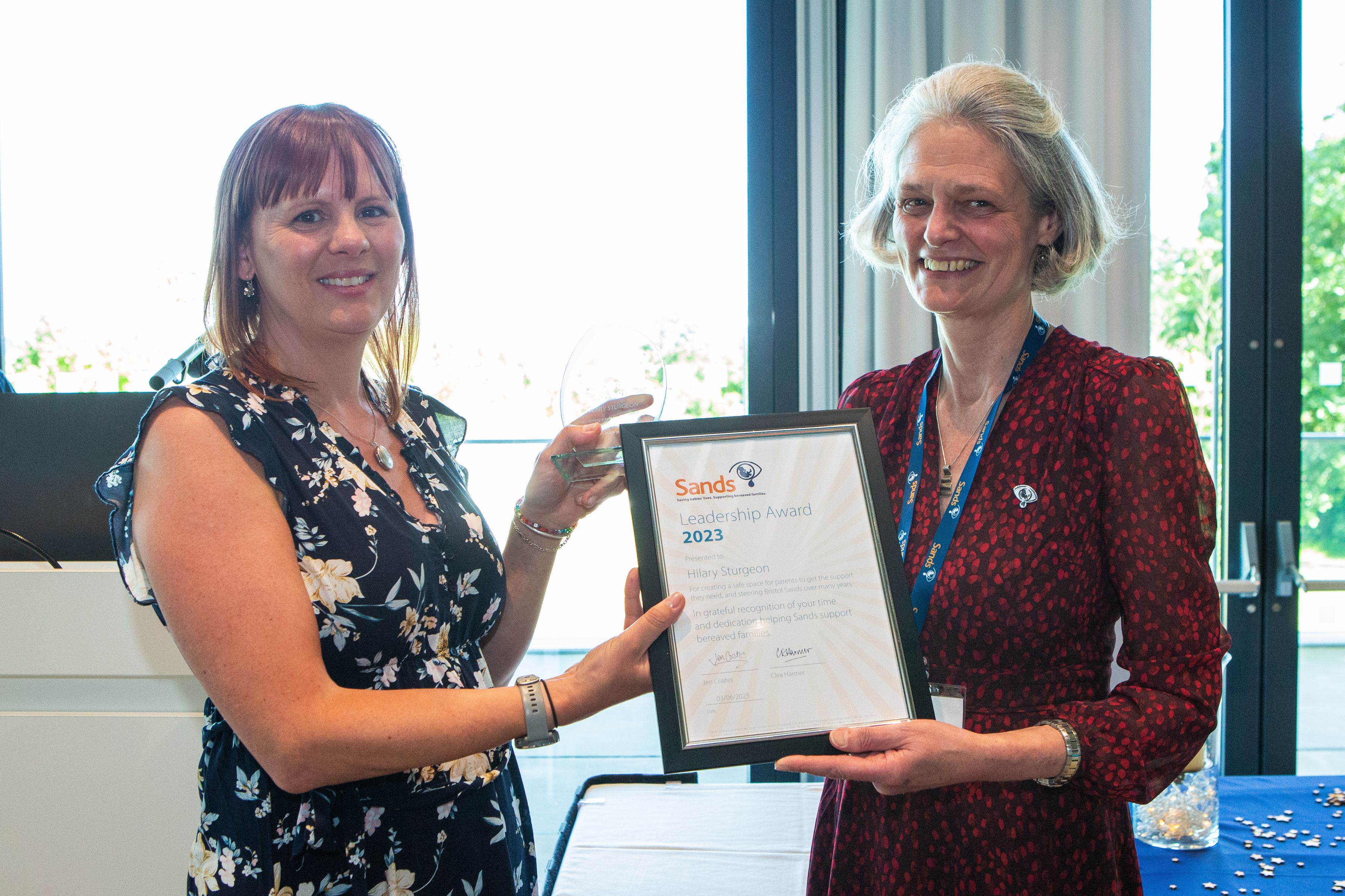 Hilary Sturgeon holding the Leadership Award Certificate standing next to Clea Harmer at the Sands Garden Day in 2023.