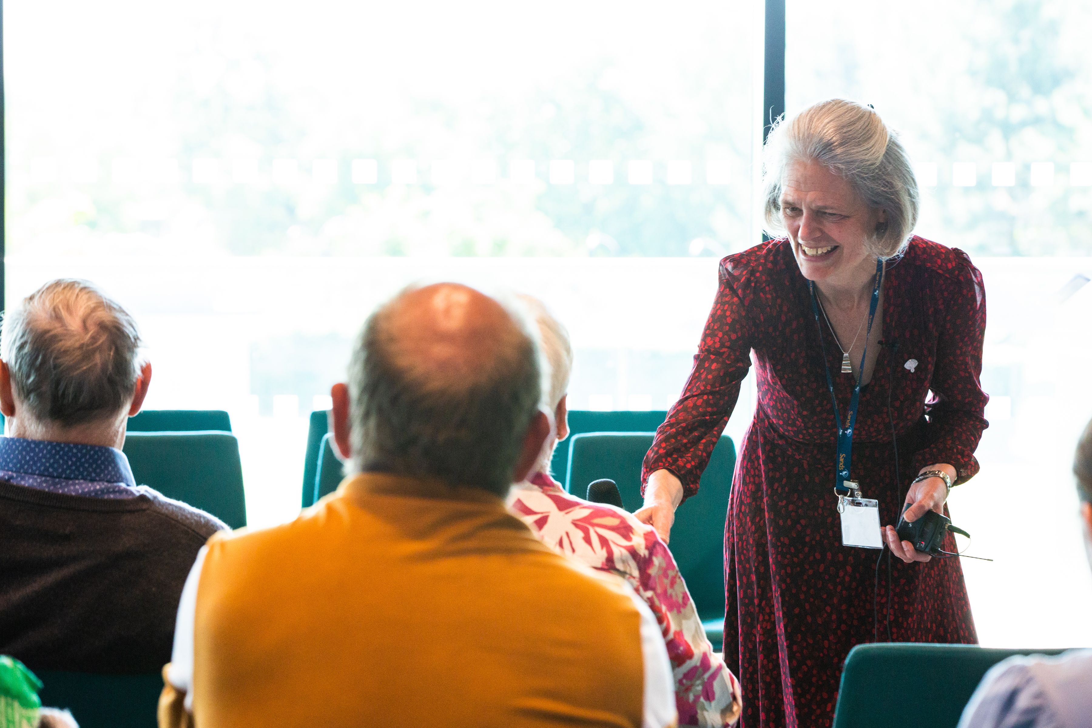 Clea Harmer smiling and handing a microphone to a supporter at Sands Garden Day.