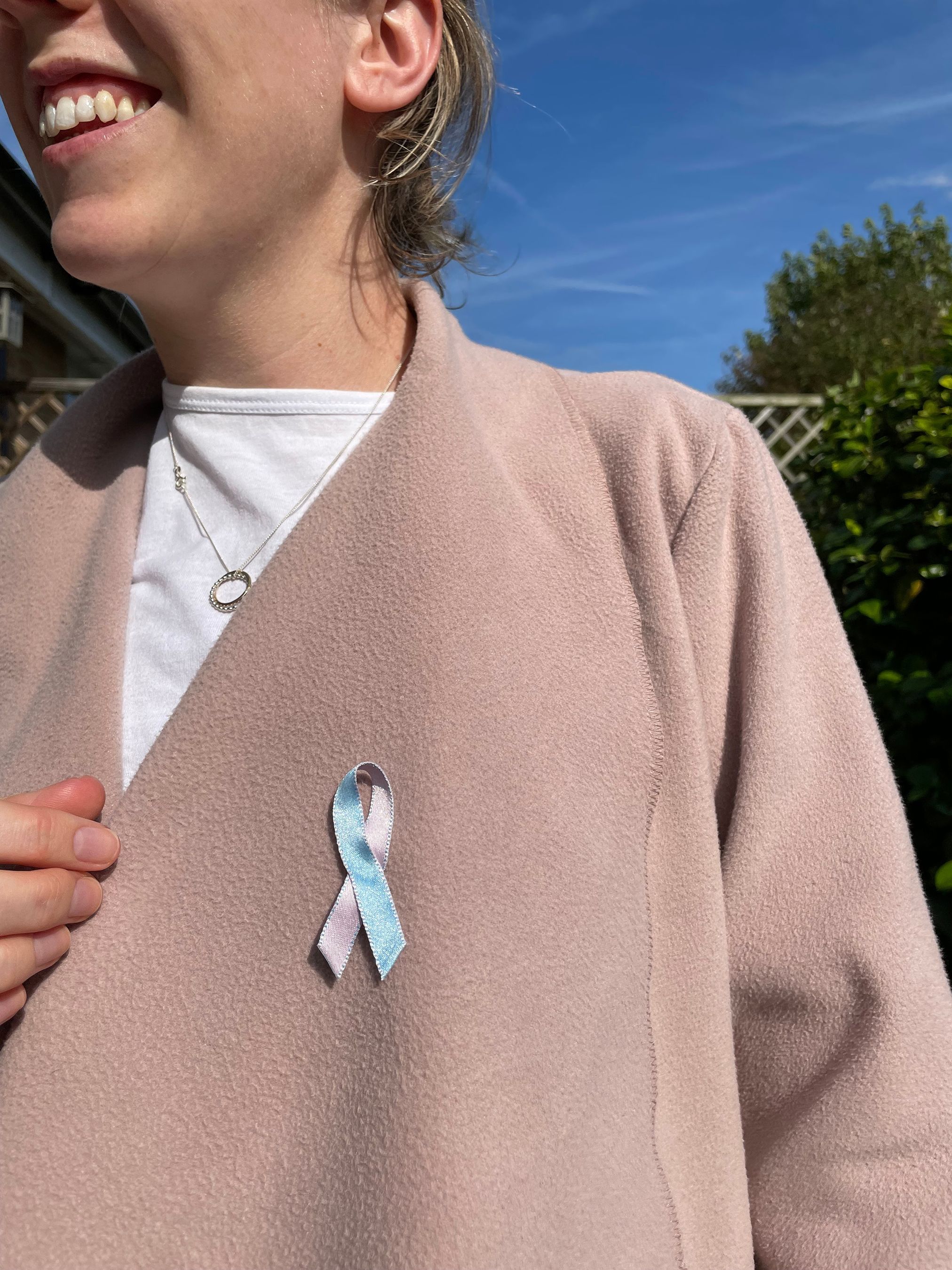 A woman wearing a fabric pink and blue ribbon to raise awareness for Baby Loss Awareness Week.  