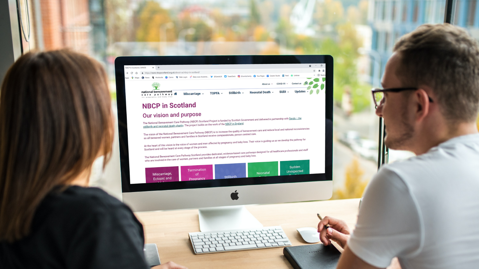 Two people visit the NBCP Scotland website on a computer.
