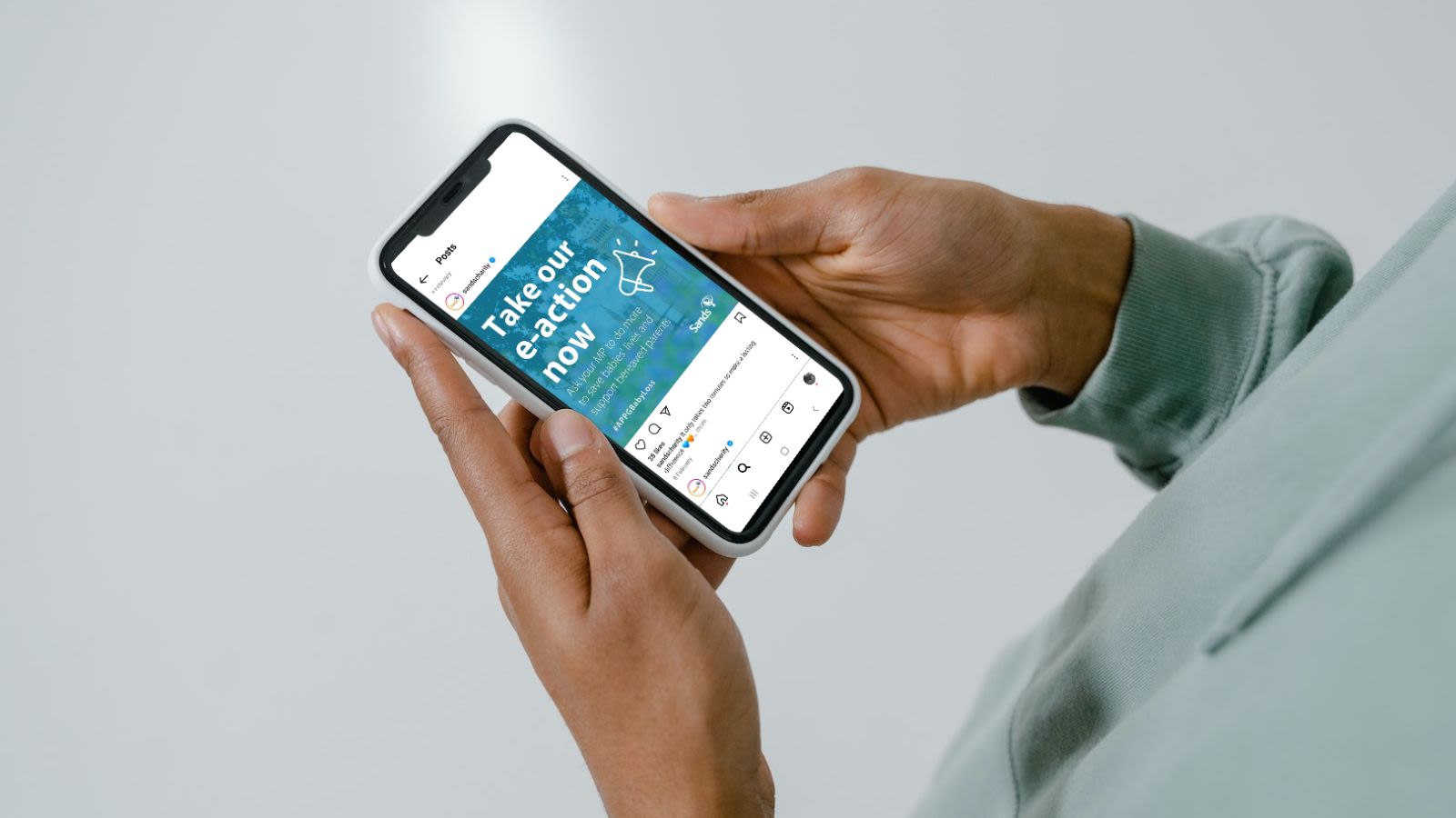 Man viewing the Sands APPG e-action Instagram posts on his mobile phone.