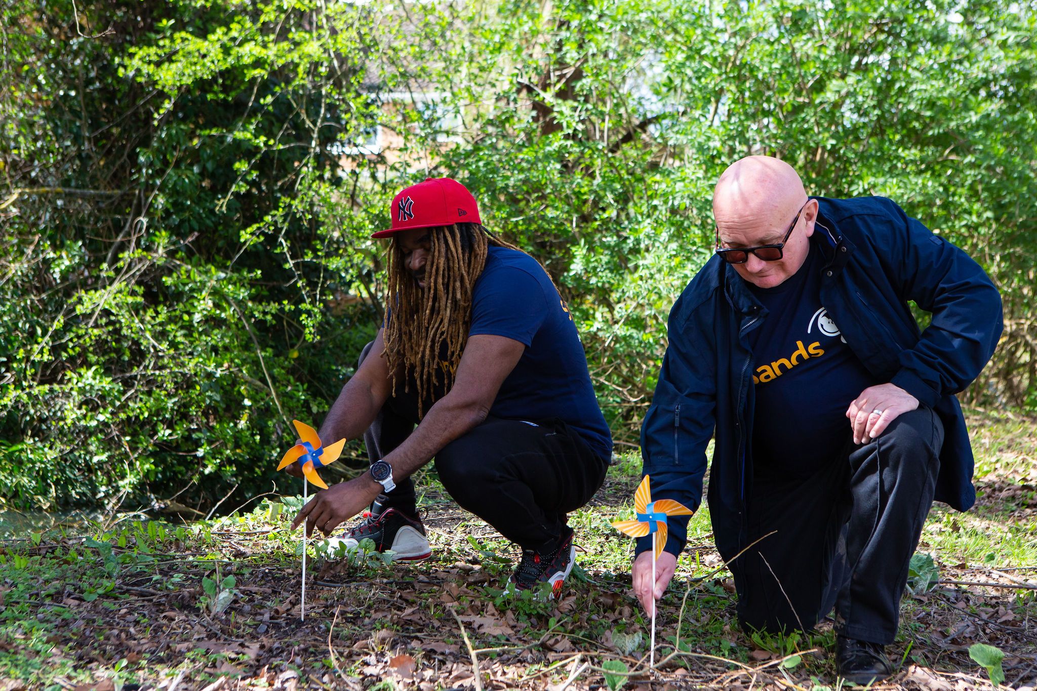 Two men kneeling and placing pinwheels into the ground.
