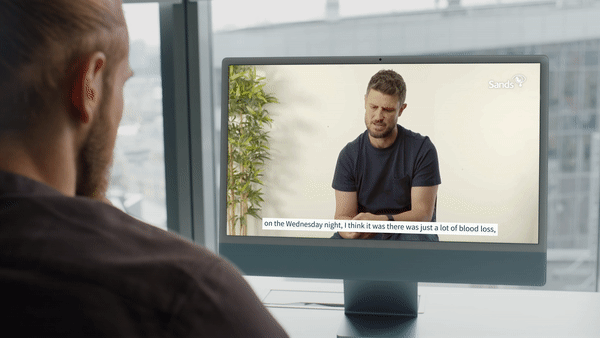 Man watching a Bereavement in the Workplace parent interview on a computer where a bereaved father is speaking about his experiences.