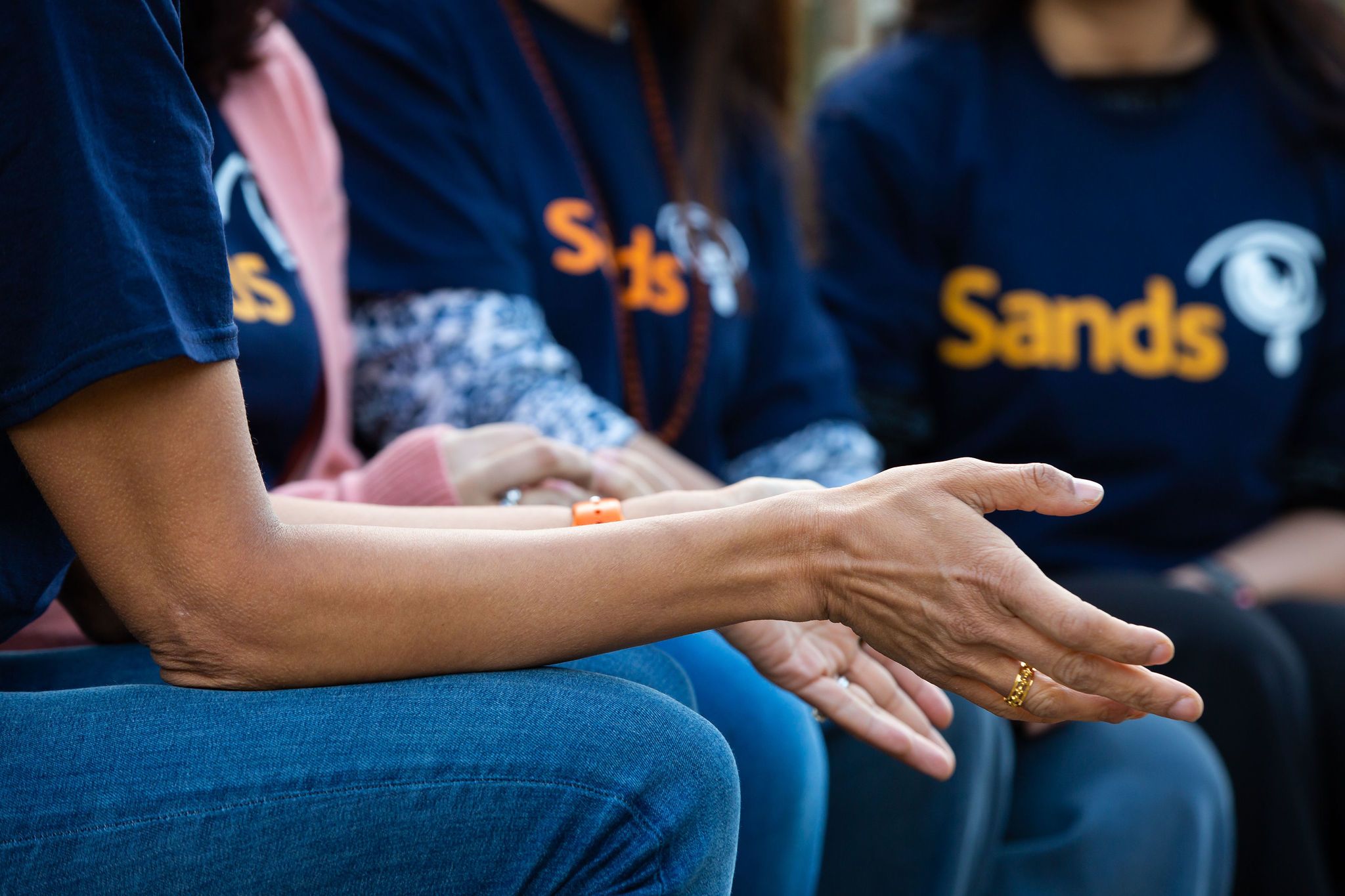 South Asian Bereaved Mothers having a conversation. They are wearing Blue Sands Tshirts.