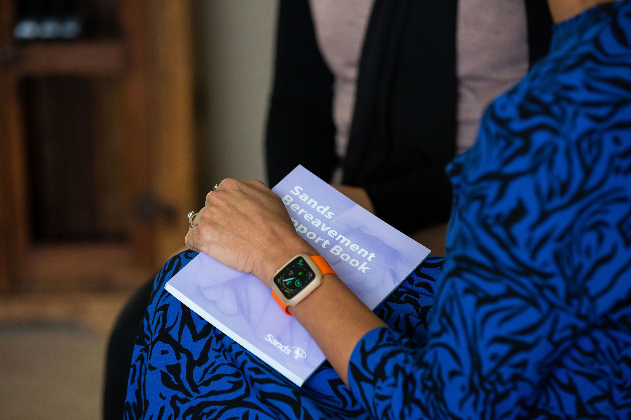 South Asian Bereaved Mother holding the Sands Bereavement Support Book in her Hand.