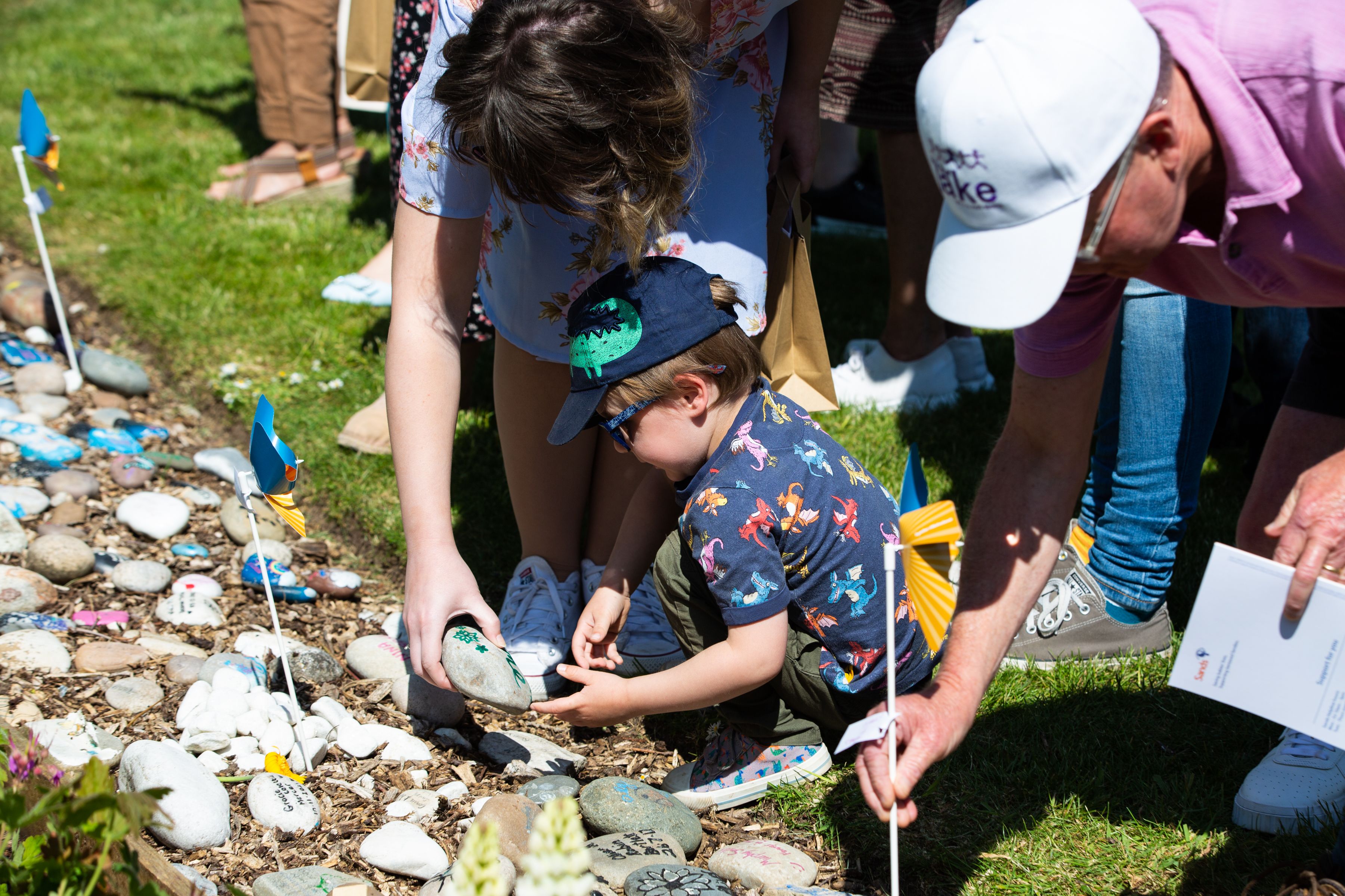 A mother and young toddler placing down a stone in the Sands Garden in remembrance during the Sands Garden Day in 2023. 