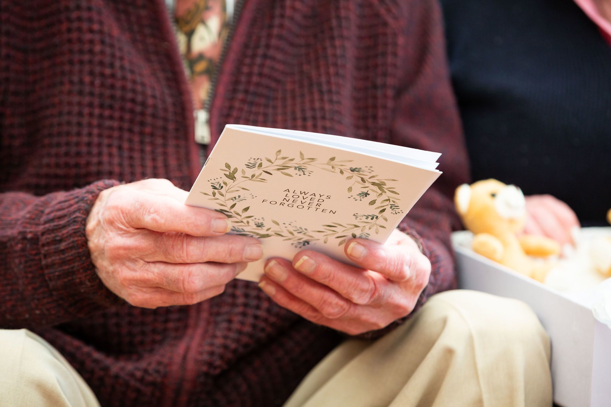 Elderly man holding a 'Always Loved Never Forgotten' booklet from the Sands Memory Box.