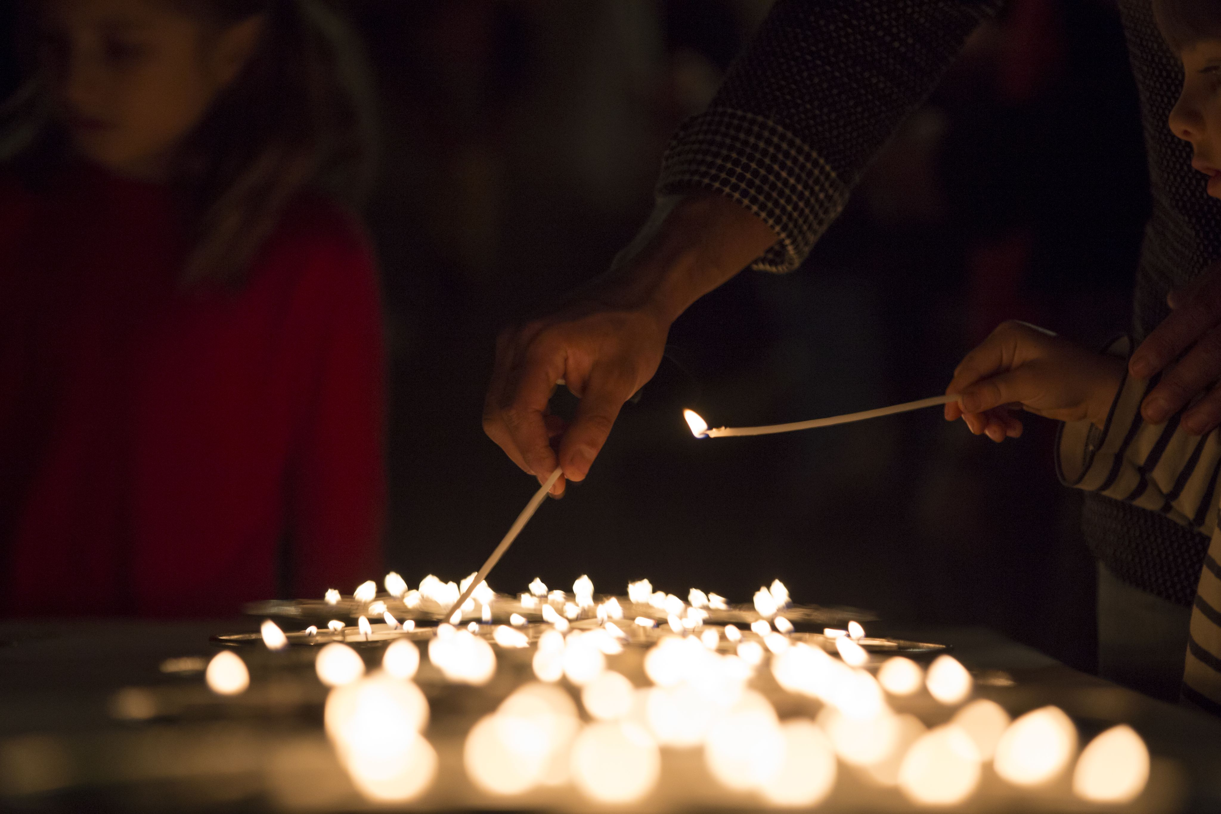 A man and a young boy lighting candles at a Lights of Love Remembrance event.