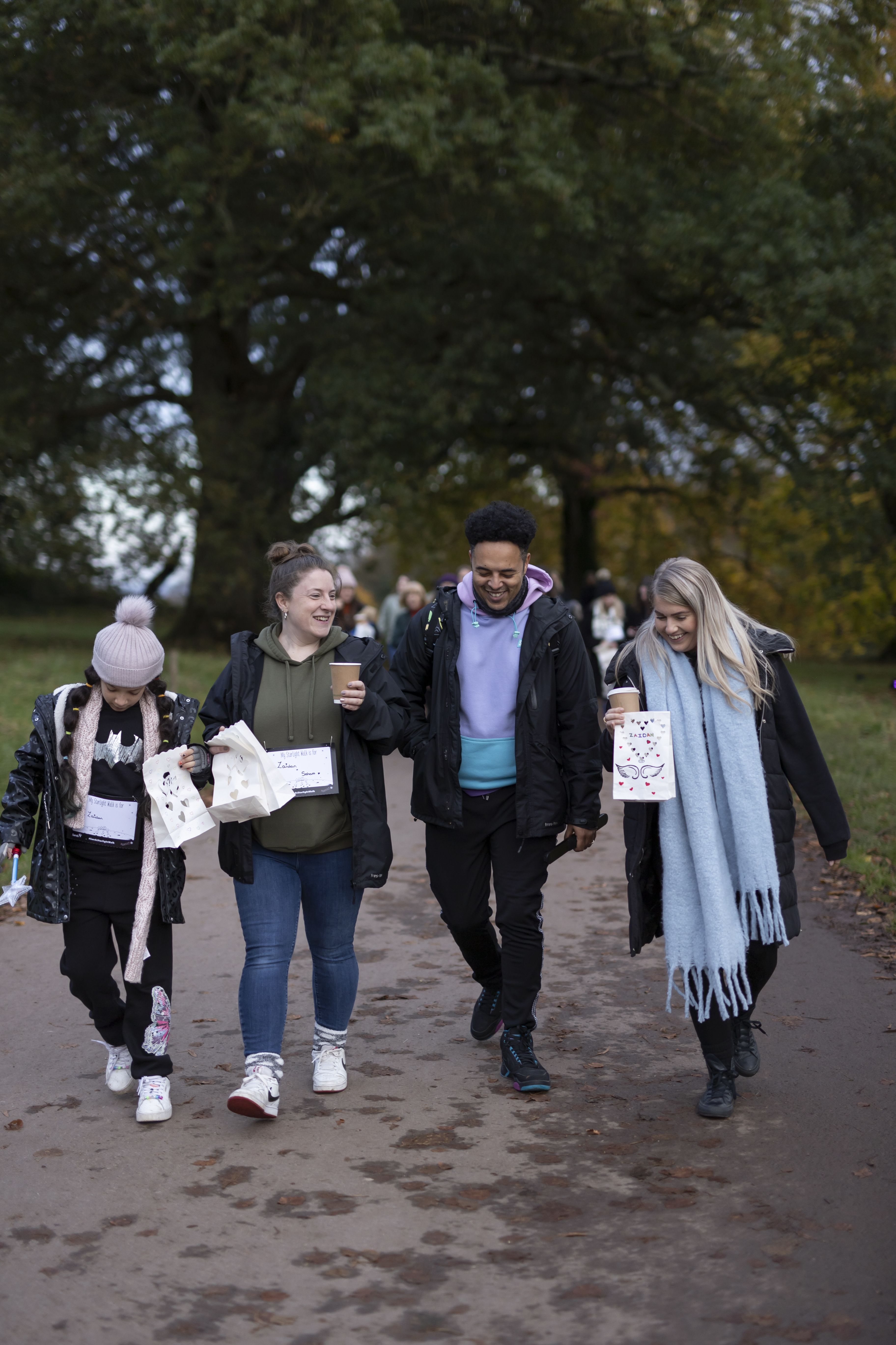 4 Sands Supporters walking and smiling at a Starlight Walk event in remembrance of their babies. 3 of them are holding paper lanterns with the babies names written on them.