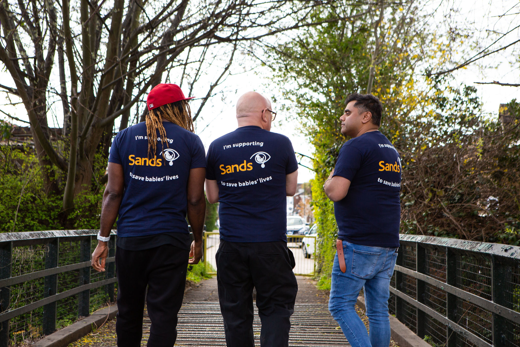 3 male Sands Supports walking alongside each other. They are wearing Blue Sands Tshirts. 